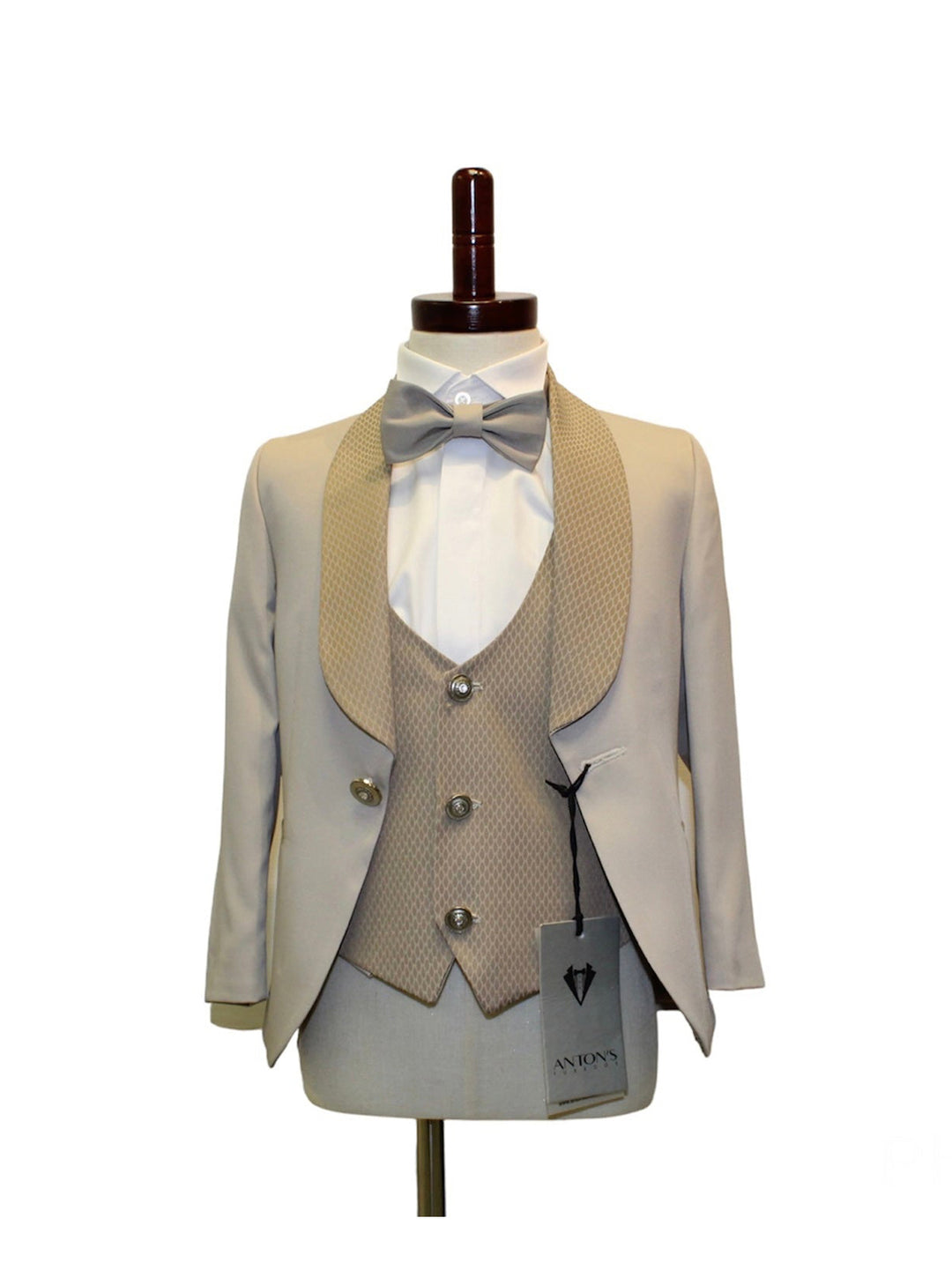 Kids beige tuxedo set on mannequin, featuring blazer, vest, bow tie, and coordinating pants, perfect for formal occasions